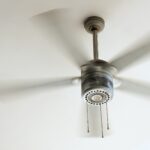 Ceiling fan in motion with blurred blades, mounted to a white ceiling.